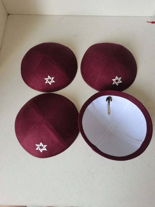 Burgundy kippahs showing a white embroidered motif and white lining