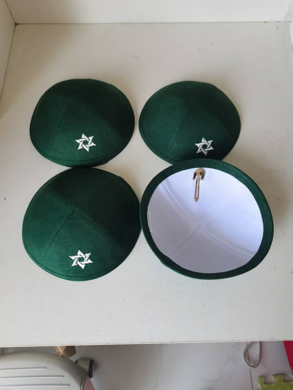 Green kippahs showing a white embroidered motif and an interior view