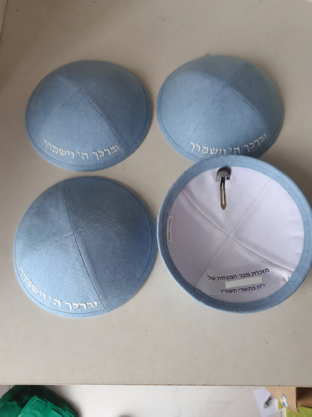 Light blue kippahs with embroidered lettering and Hebrew interior printing; interior name hidden